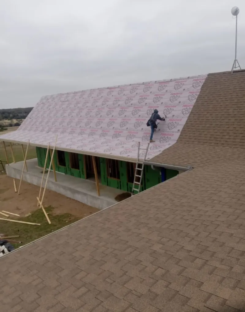 Worker preparing underlayment for a metal roof installation in Menominee